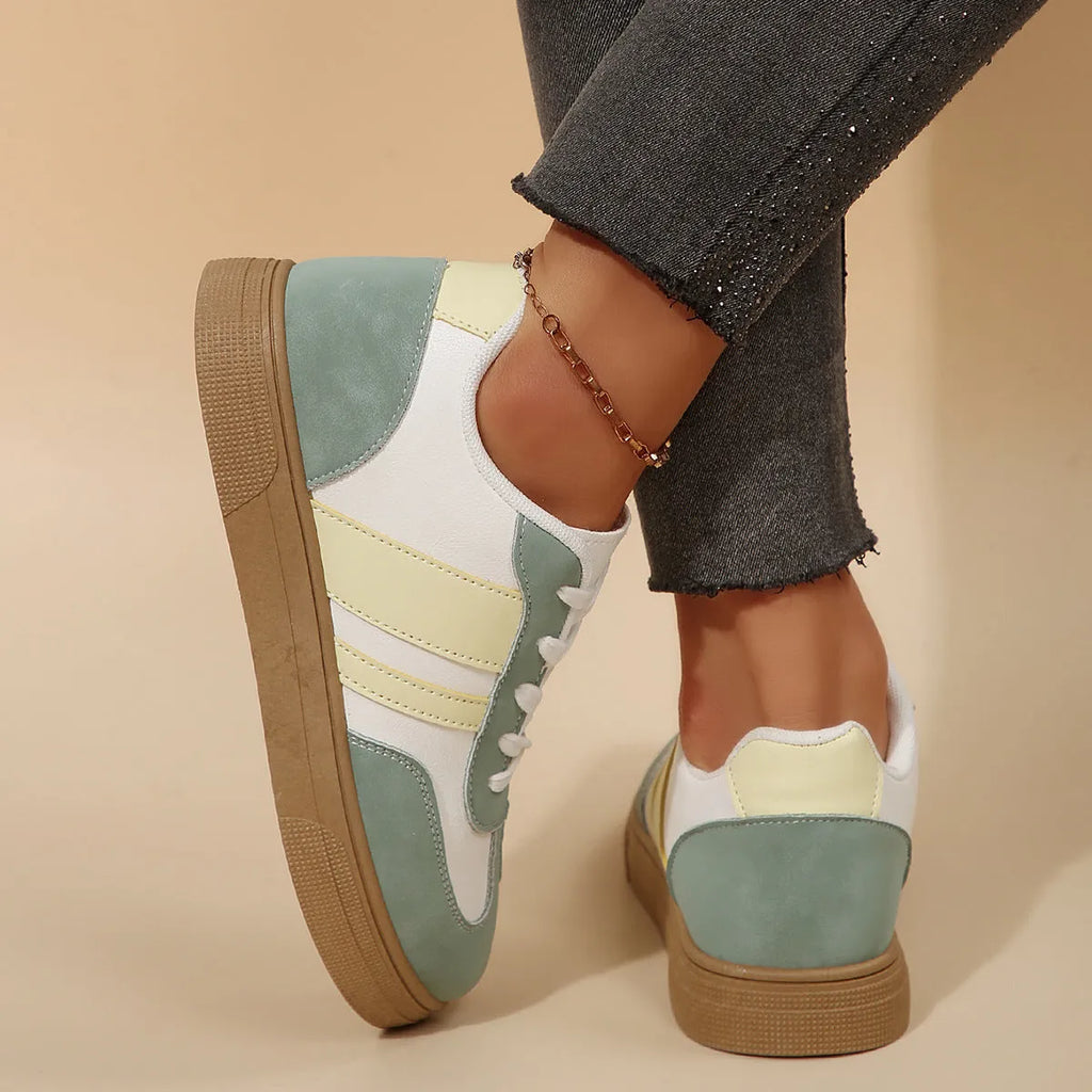 Green women's retro low-top trainers with cross-strap detail and round toe on a white background.