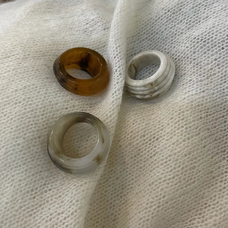 Chinese style irregular geometric wide resin ring in brown or white on a plain background.