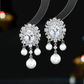 Oval geometric earrings with zircon inlay, pearl details, and tassel design in light purple colour