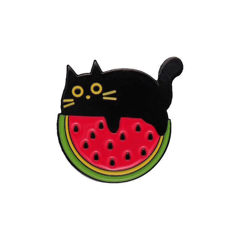 Colourful cartoon fruit design metal letter brooch on a fabric background.