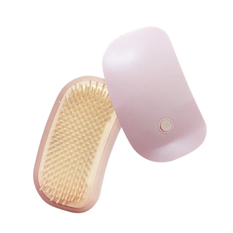 Pink handheld electric pet grooming brush with TPE comb teeth on a white background