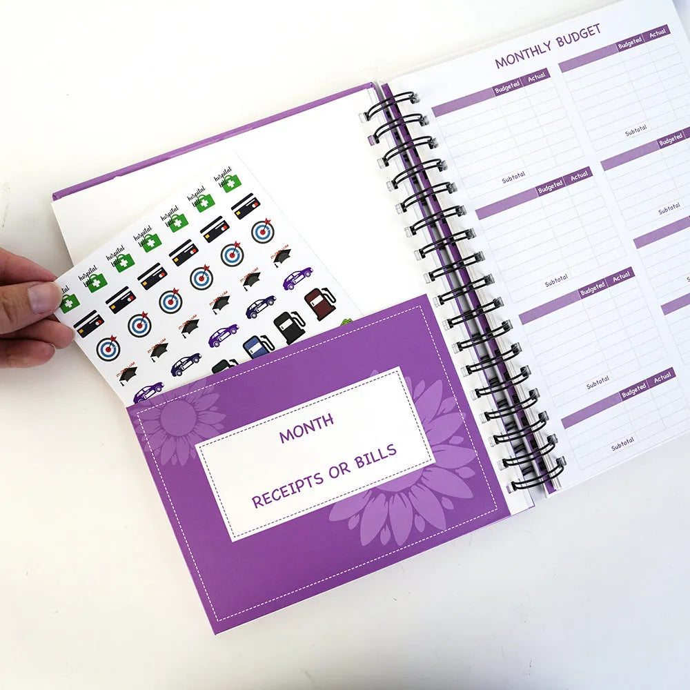 Purple coil-bound financial planning notebook with pen, stickers and paper clips for monthly budgeting
