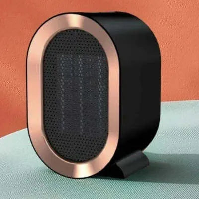 Compact black desktop ceramic fan heater with mechanical control dials, placed on a wooden desk.