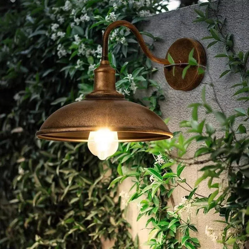 Retro style outdoor wall lamp in a copper finish with an oblique angle mount on a garden wall.