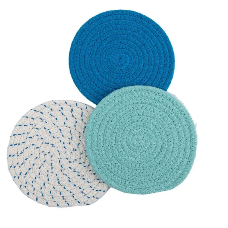 Three round grey cotton cord coasters placed on a wooden table, each 18cm in diameter.