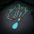 Turquoise blue large water drop pendant on a long mixed-material bead necklace.