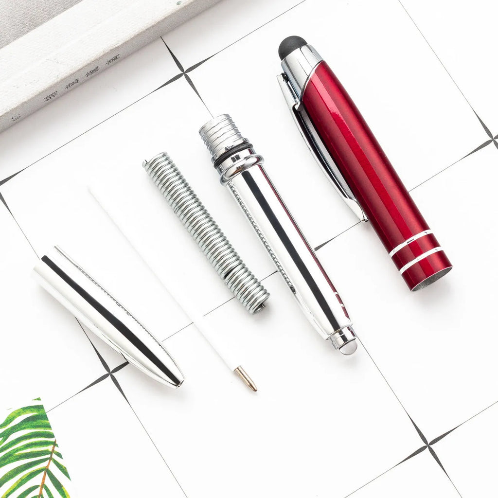 Red metal ballpoint pen with a capacitive stylus tip and built-in LED light on a desk.