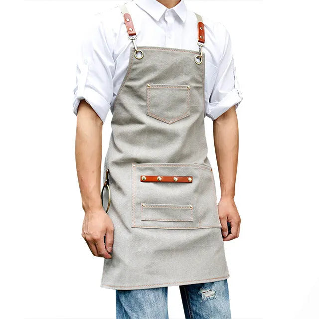 Canvas apron with cross-back straps in camel colour.