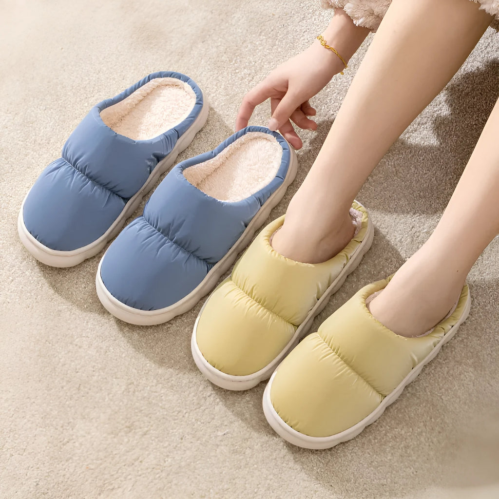 A pair of thick-soled indoor slippers with an artificial leather upper and soft plush lining, shown in a choice of colours.