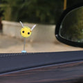 Small yellow and black fur ball bee car decoration on a plastic surface.