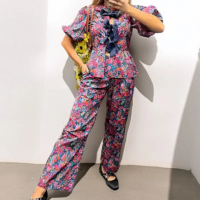 Women's floral print trousers suit with a tie-neck puff sleeve top and matching trousers