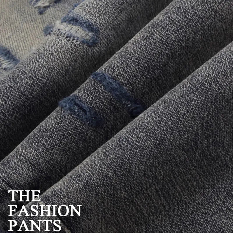 Slim-fit light blue jeans with a worn wash, knee holes, patch details, and embroidered branding on the leg.