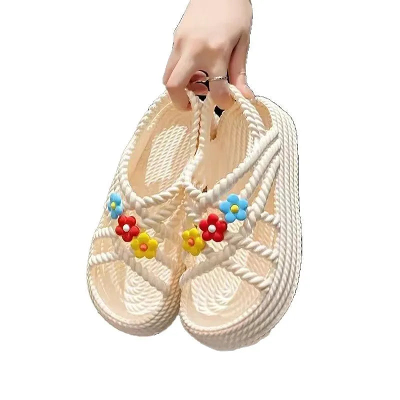 Beige PVC sandals with flower embellishments and a round toe, on a non-slip sole.