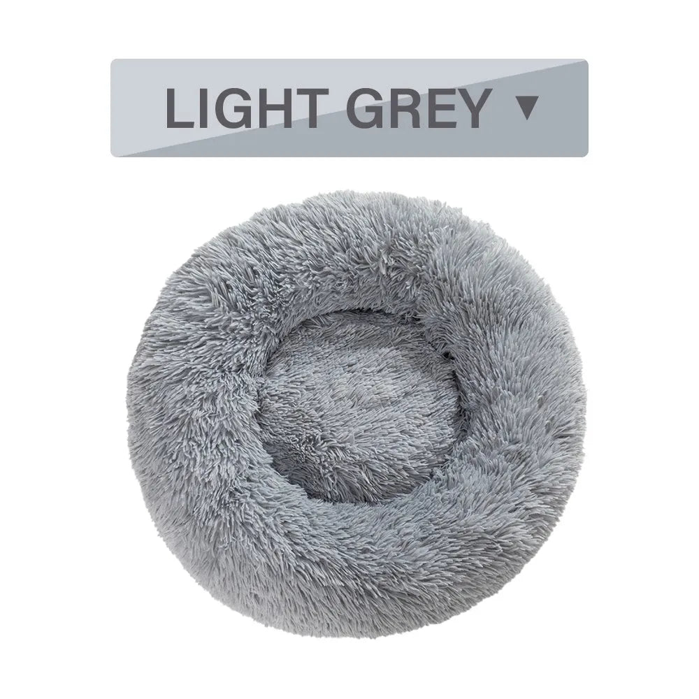 Fluffy donut-shaped dog bed in light grey plush material, showing raised rim and central cushion.