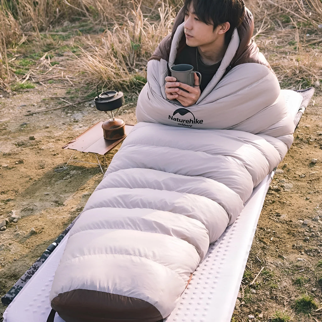 Goose down mummy sleeping bag for adults shown with its storage bag.