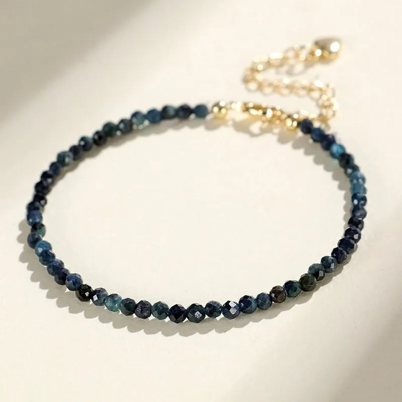 Close-up of a 3mm blue tourmaline cut bead spacer bracelet on a wrist.
