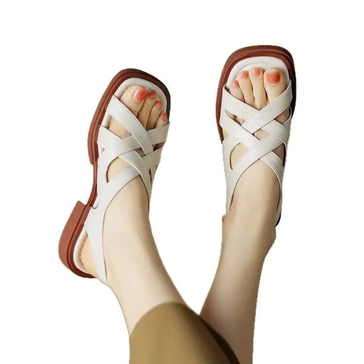 Women's glossy black patent leather sandals with square toe and cross ankle strap.