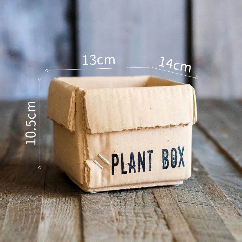 Cement brown paper box style flowerpot with angular sides and a perforated base on a floor.