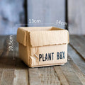 Cement brown paper box style flowerpot with angular sides and a perforated base on a floor.
