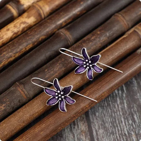 A pair of purple flower-shaped alloy drop earrings with a retro design on a white background.
