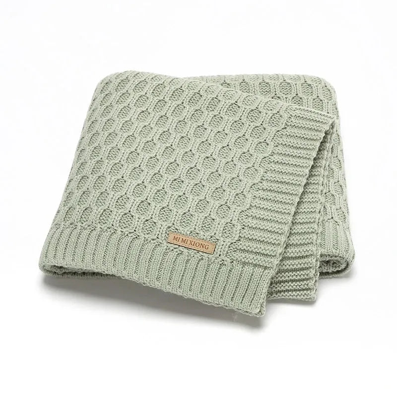 Solid colour infant hug blanket with three-dimensional lines, shown in one of five colour options.