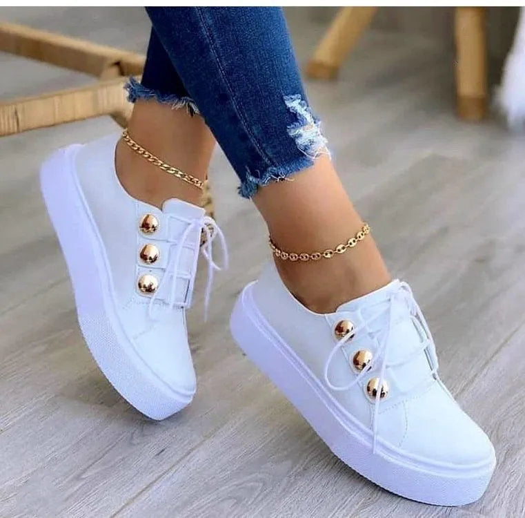Women's white lace-up flats sneakers with decorative rivet detailing on casual shoe