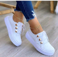 Women's white lace-up flats sneakers with decorative rivet detailing on casual shoe