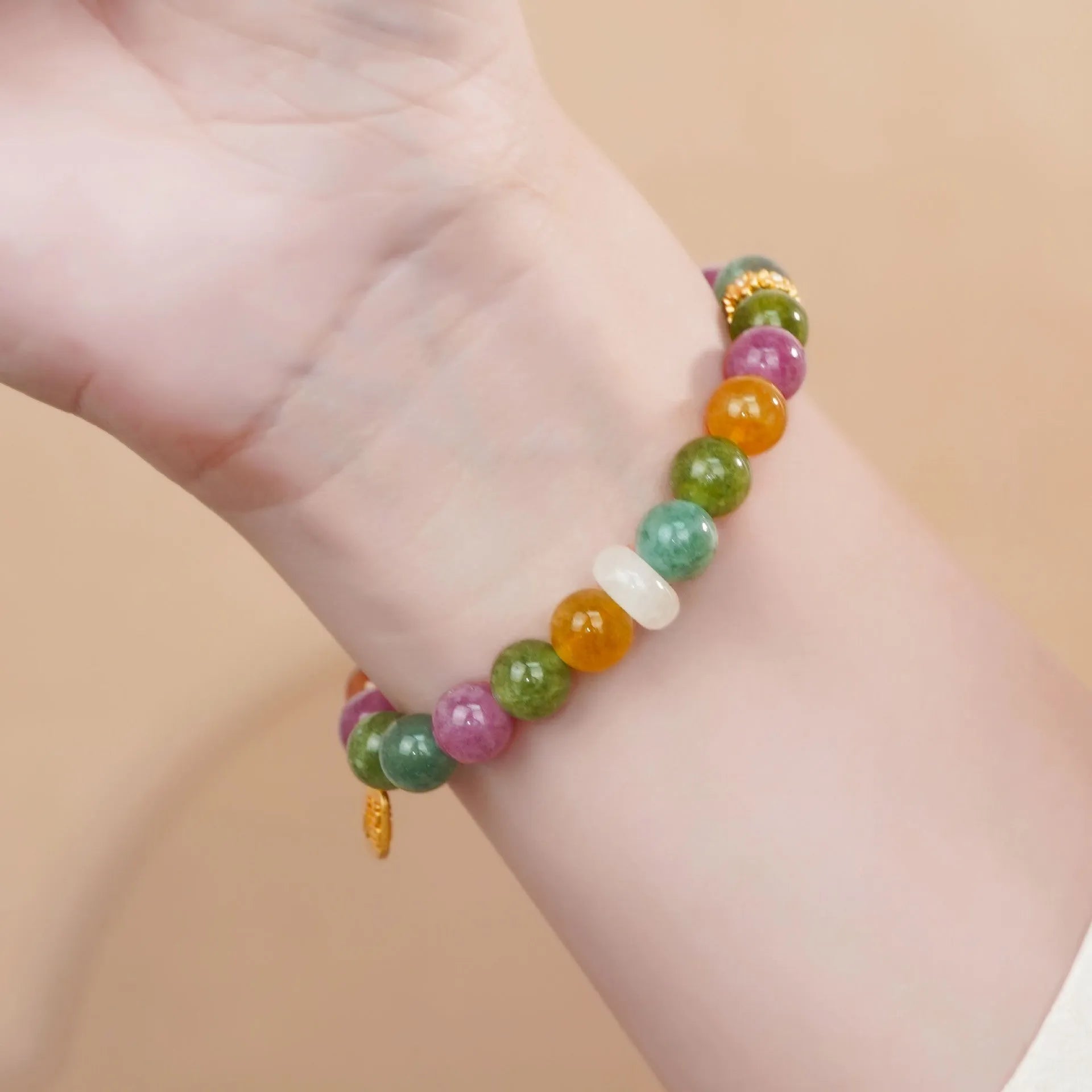 Natural rainbow-coloured tourmaline and jade half bracelet for women on a wrist.