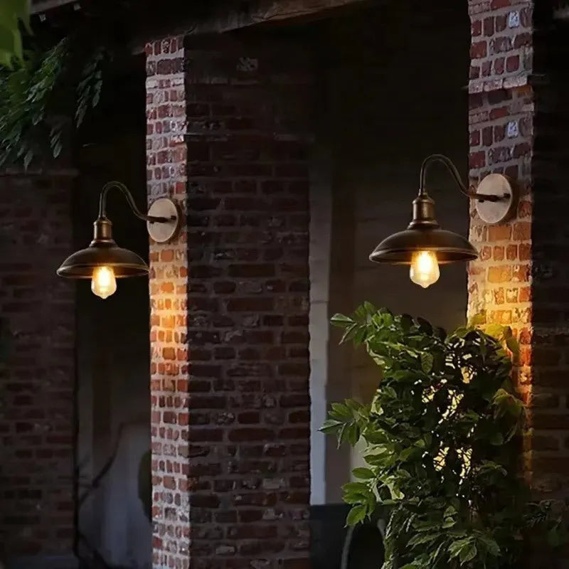 Retro style outdoor wall lamp in a copper finish with an oblique angle mount on a garden wall.