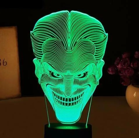 A 3D LED table lamp showing multiple colour lights, sitting on a square base with a USB cable and remote control.