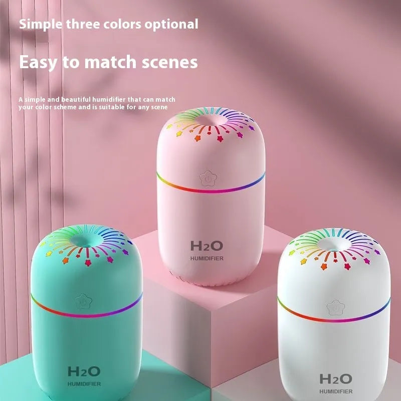 White USB mini humidifier with water tank on a desk next to a laptop