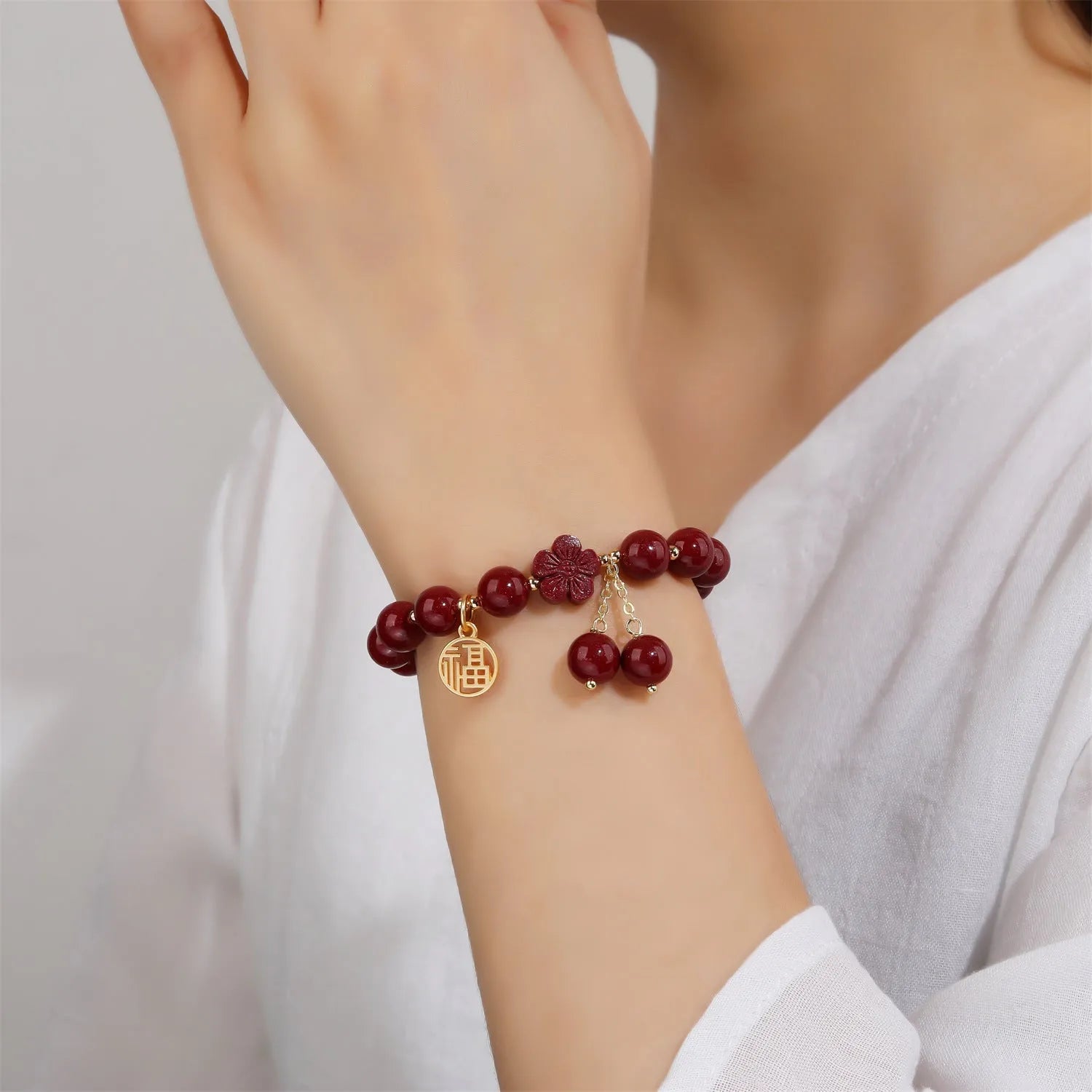 Close-up of a retro-style women's cinnabar bracelet with purple gold sand colour, showing fu character design and tassels.
