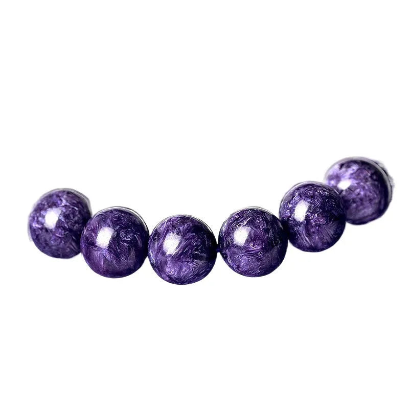 Natural transparent charoite crystal bracelet with platinum-coloured clasp on a wrist.