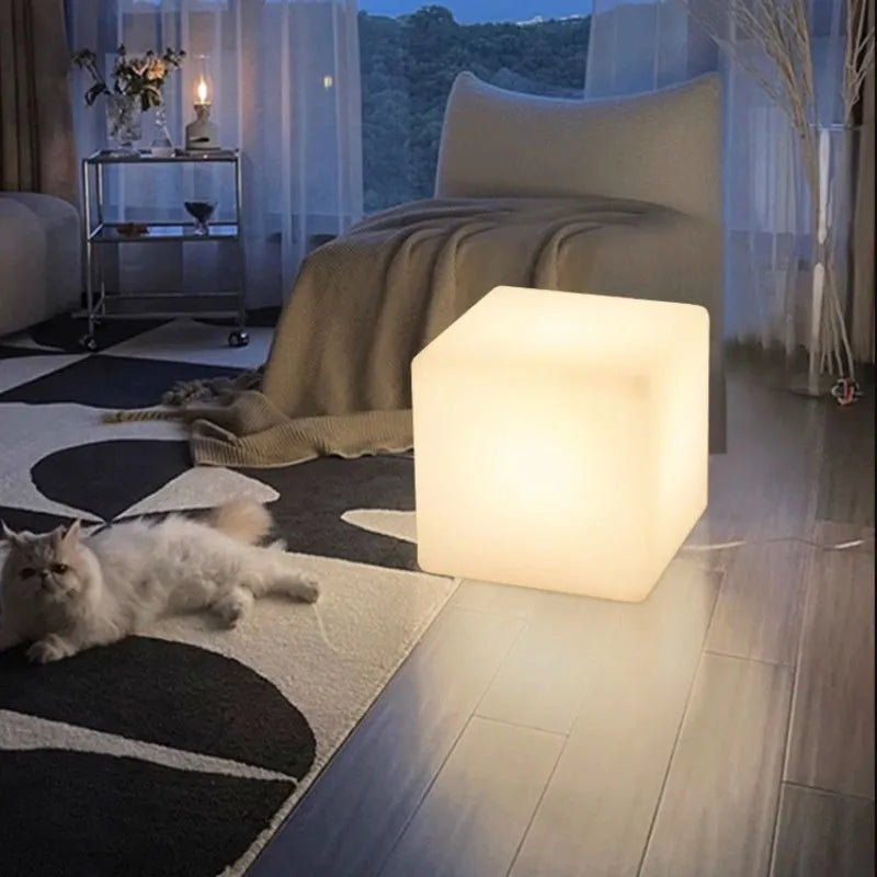 A white, square LED cube light stool with a modern design, shown outdoors on a patio.