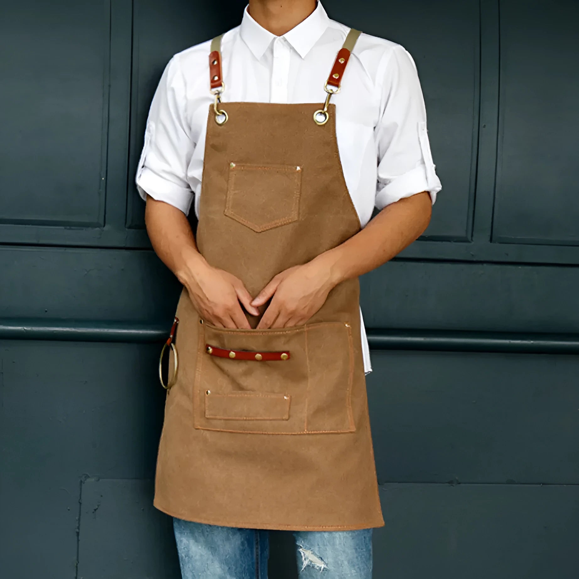 Canvas apron with cross-back straps in camel colour.