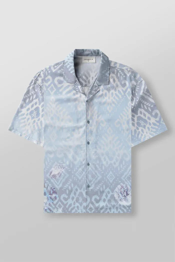A man modelling a loose-fitting, short-sleeved beige cardigan with a printed floral pattern.