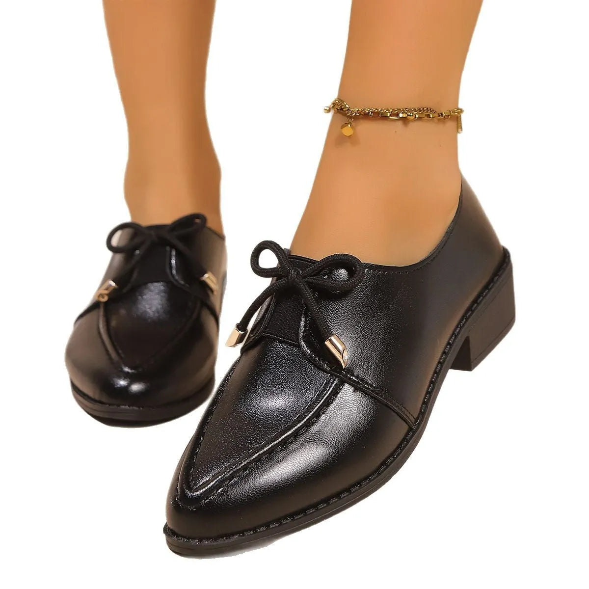 Women's classic black slip-on flat shoes with a large decorative bow on the toe.