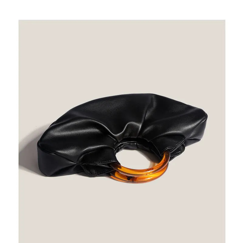 Niche horn bag in black or white PU leather with acrylic ring handle and fold detail for daily matching.