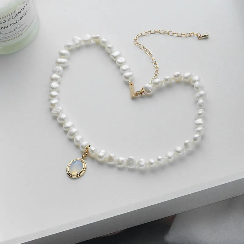 Round geometric sterling silver necklace with an irregular white pearl pendant on a chain.