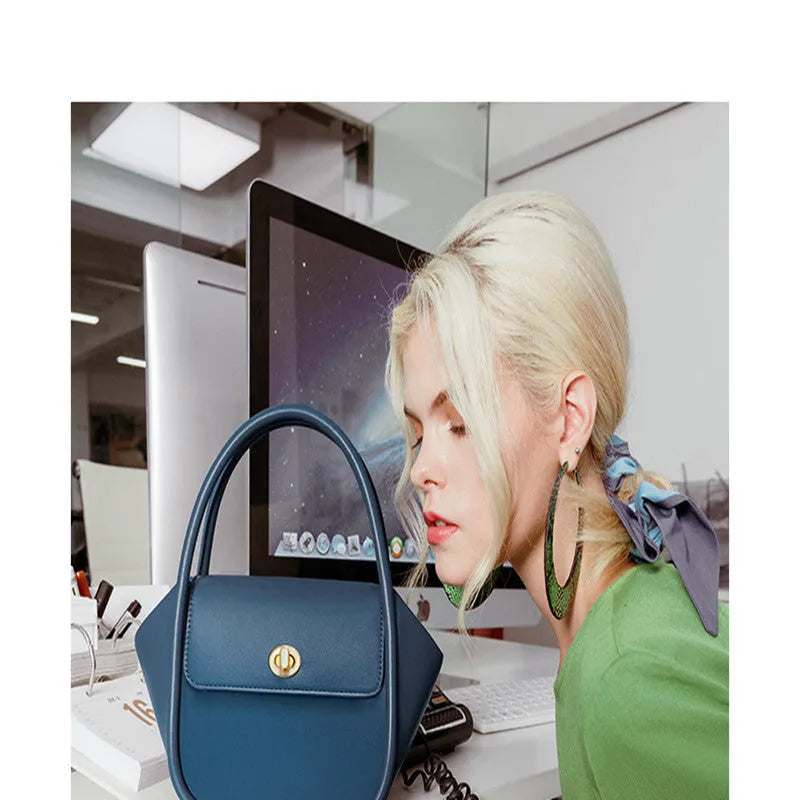 A women's cow leather wing-shaped handbag with a latch closure and a single shoulder strap.
