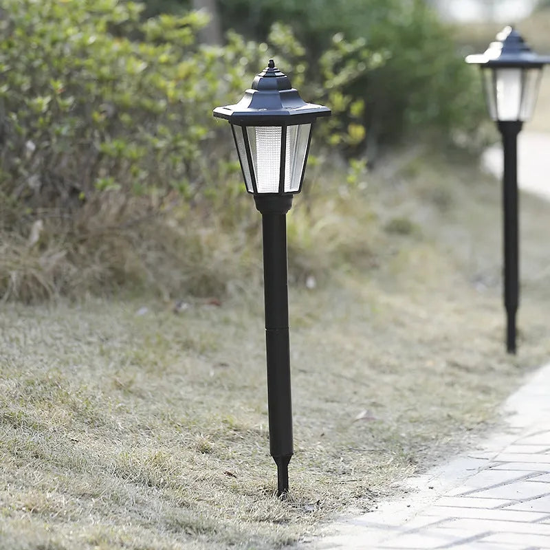 Outdoor solar hexagonal wall light in garden setting, available in white or yellow light, with ground plug or wall hanging style