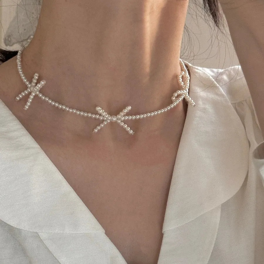 White geometric bow detail on an adjustable imitation pearl necklace for women, chain length 31-40cm.