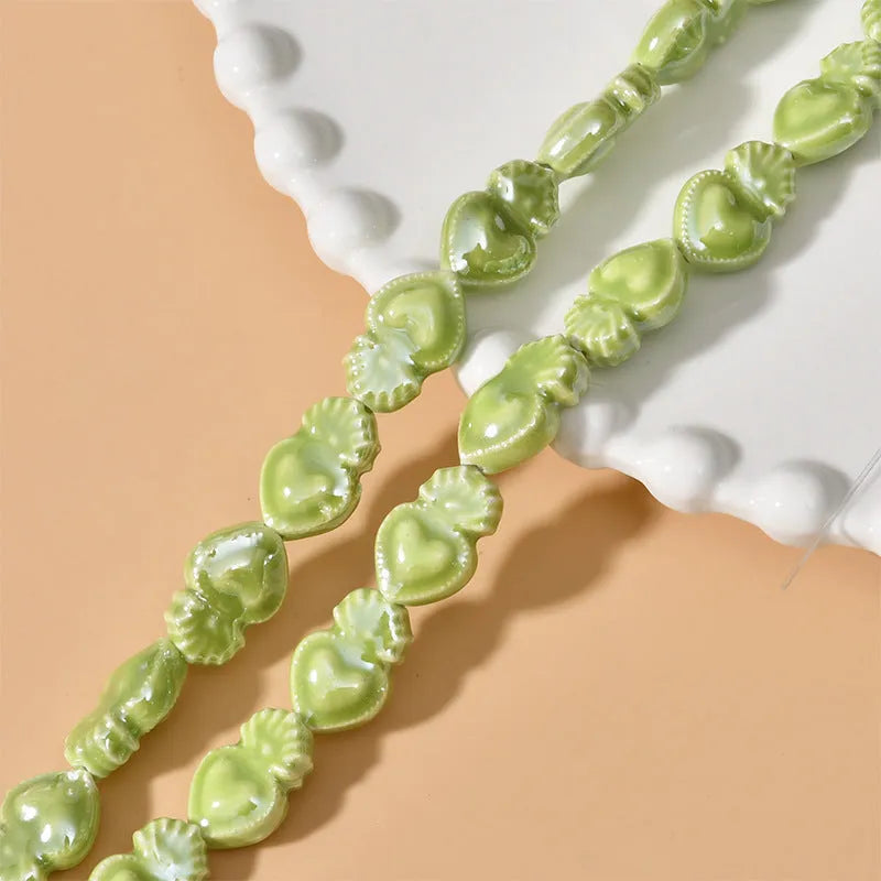 Small heart-shaped ceramic beads in multiple colours showing straight hole, approximately 10mm by 15mm size