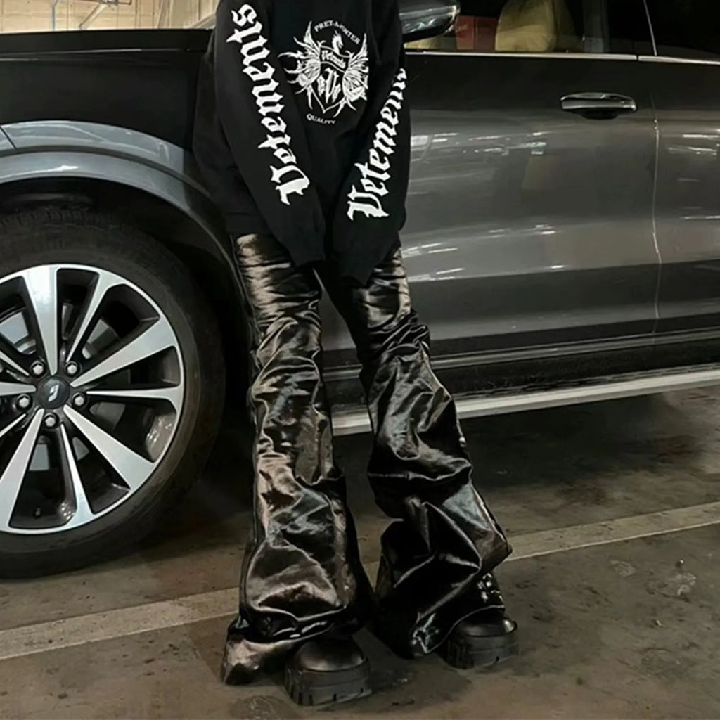 Black shiny patent leather coated skinny jeans on a denim background.