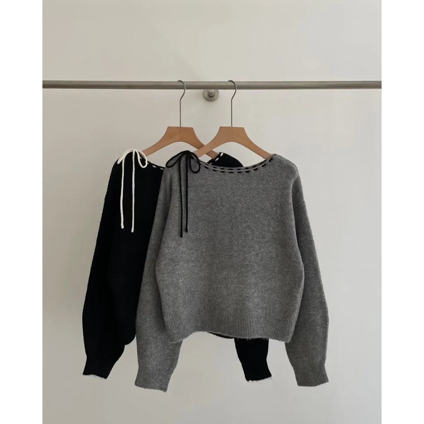 A grey loose-fitting women's knitwear pullover, shown on a hanger.
