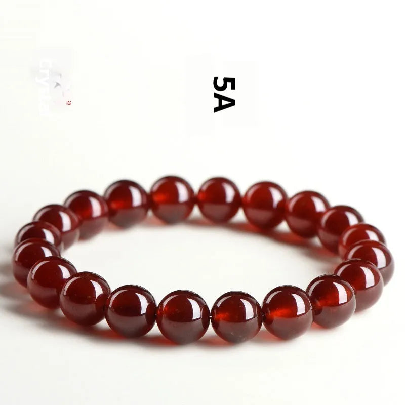 Natural orange red garnet crystal bracelet with Ruyi charms on a white background.