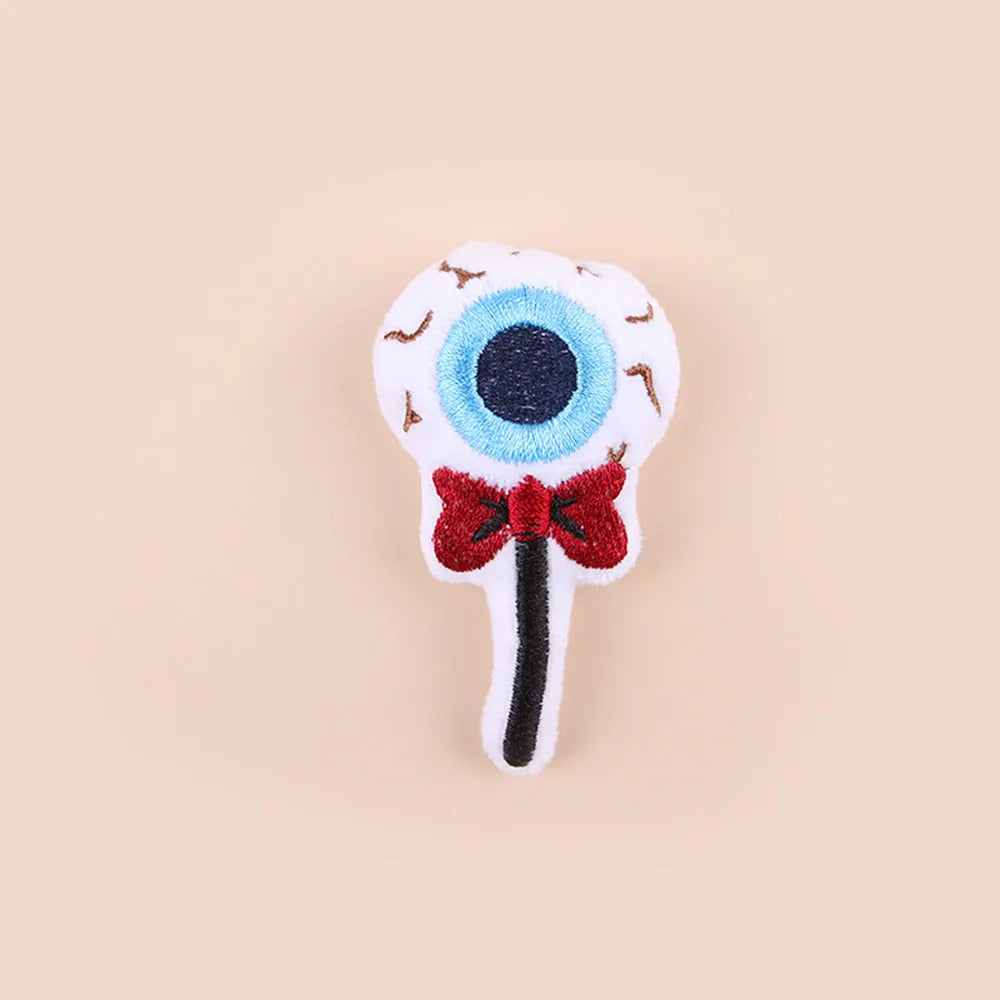 Plush cat teaser toy with candy, eyes and skull attachments on handheld wand