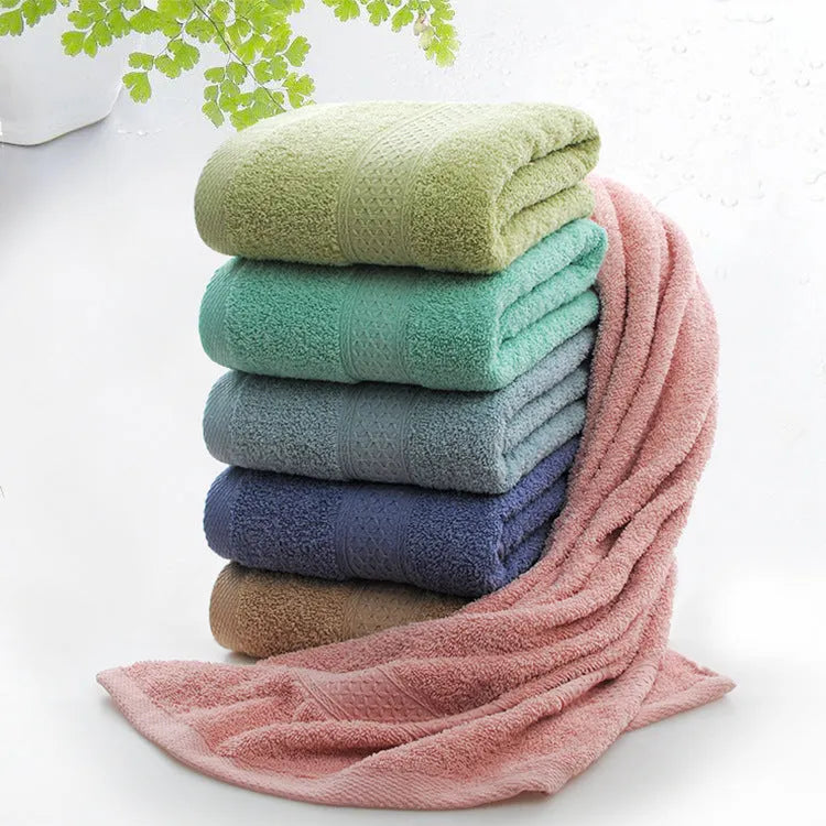 A pile of thickened cotton bath towels in various colours including apple green, dark blue, and light pink.