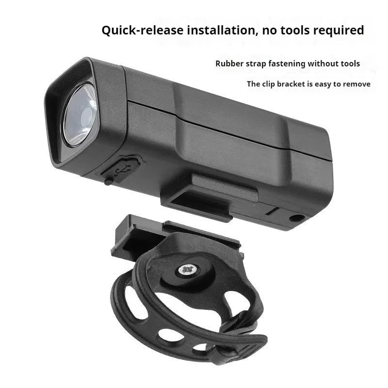 A black USB rechargeable bicycle headlight with a quick-release strap mount on a handlebar.