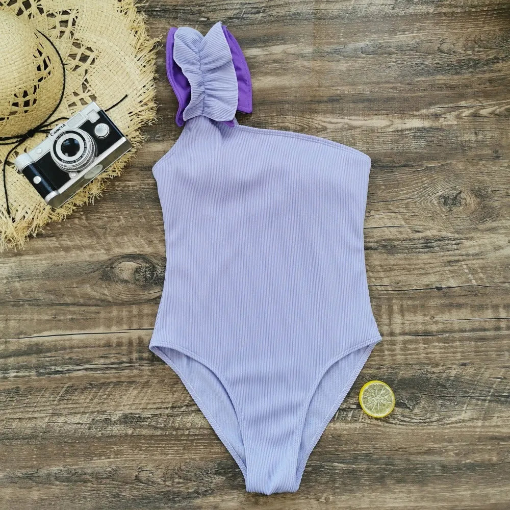 A blue women's one-piece swimsuit with a single suspender strap and a high-waist cut on a mannequin.